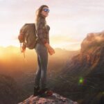 Hiker at summit peak, looking at sunset